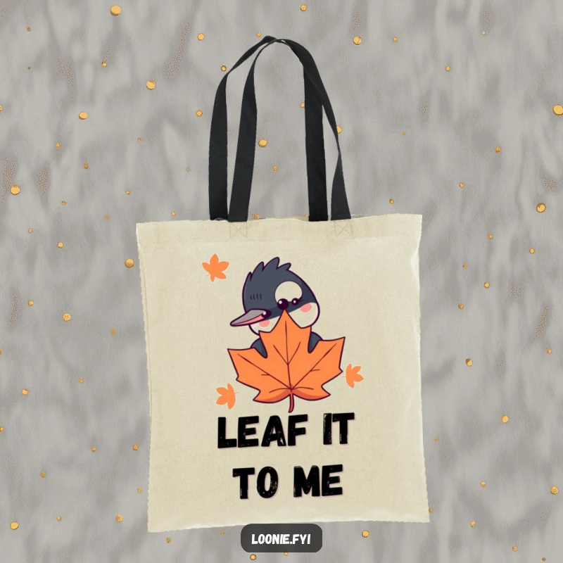 Funny tote bag featuring a curious loon peeking behind a maple leaf, perfect for carrying books or groceries with a smile.